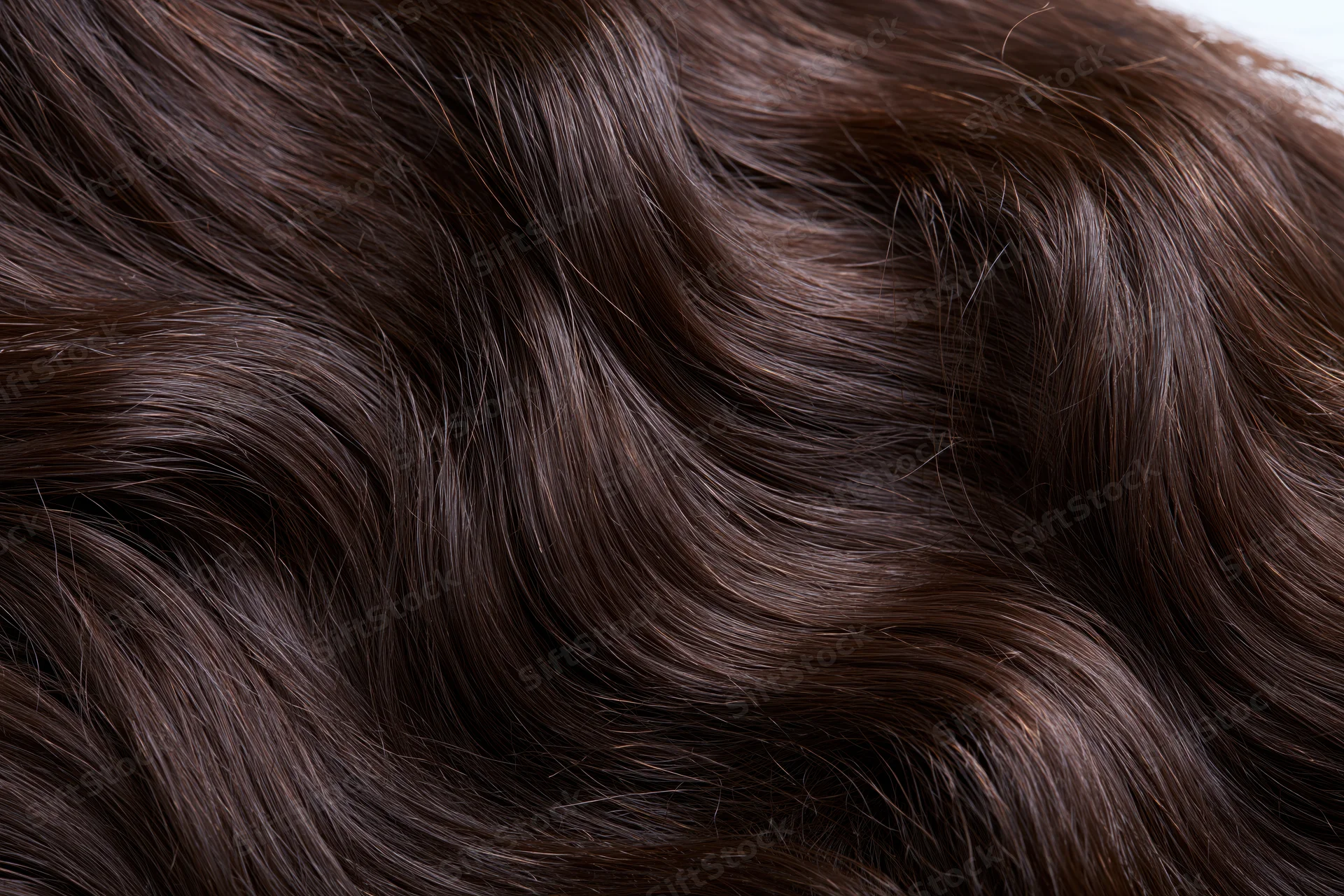 Close-up of dark brown wavy human hair filling the frame