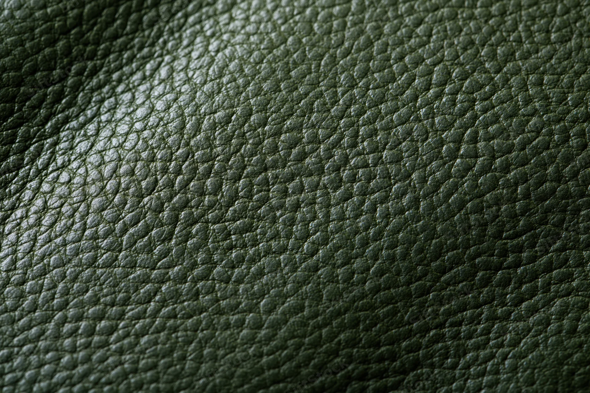 Close-up of dark forest green leather surface showing pebbled texture and grain pattern