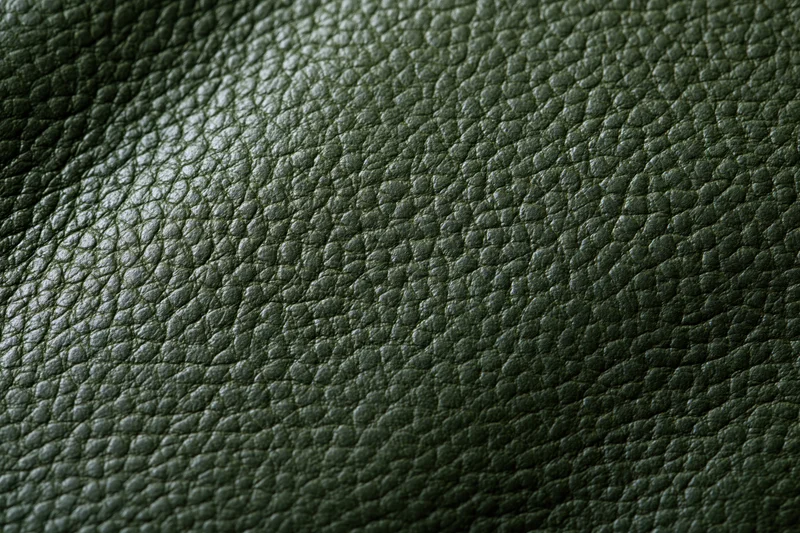 Close-up of dark forest green leather surface showing pebbled texture and grain pattern