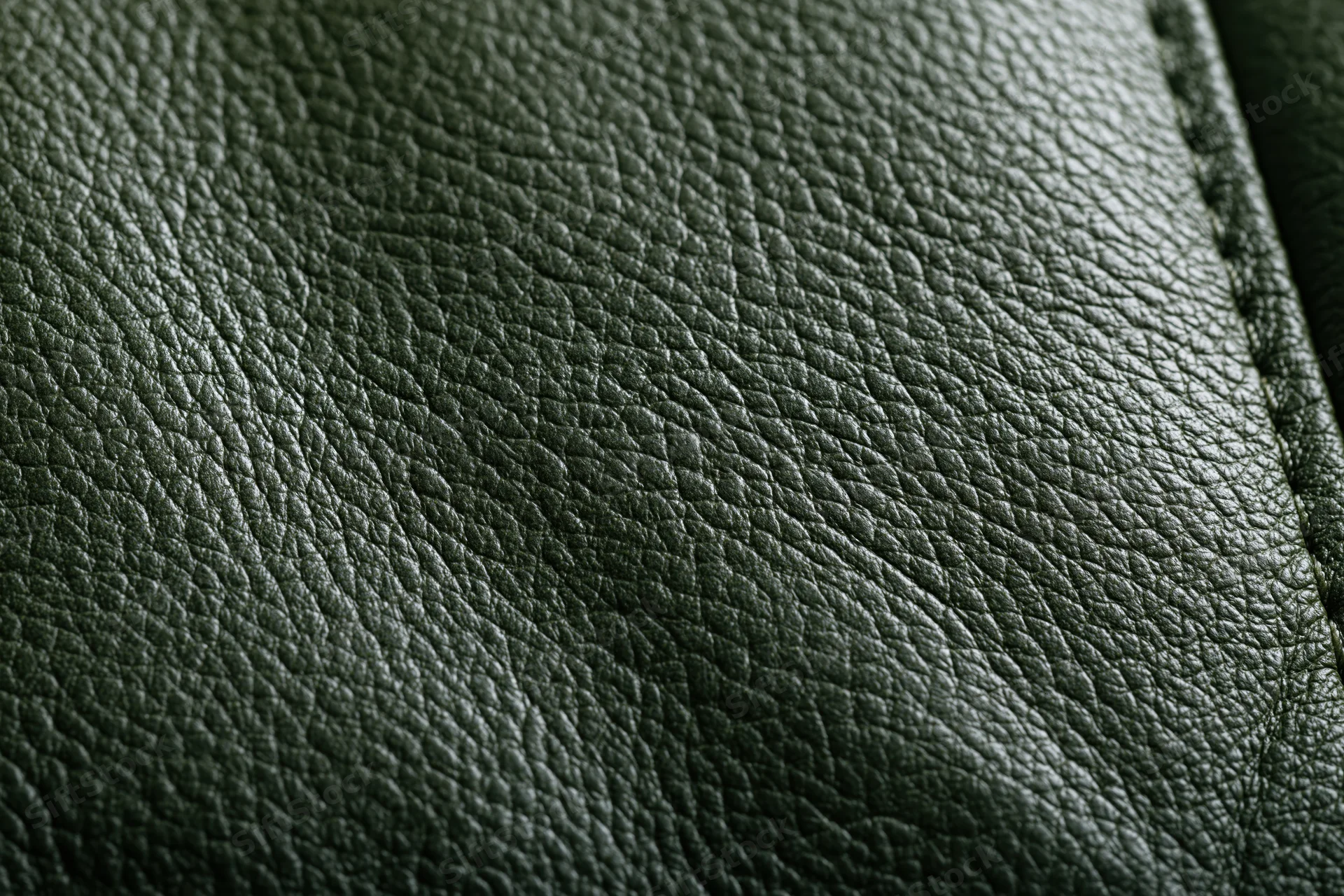 Close-up of dark forest green leather surface with visible grain and stitching