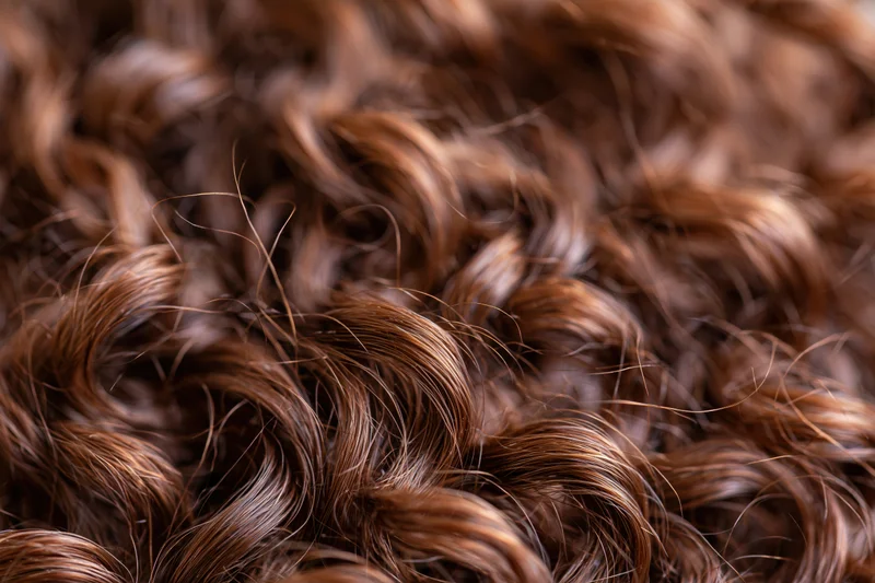 Close-up of dense curly brown hair strands filling the frame