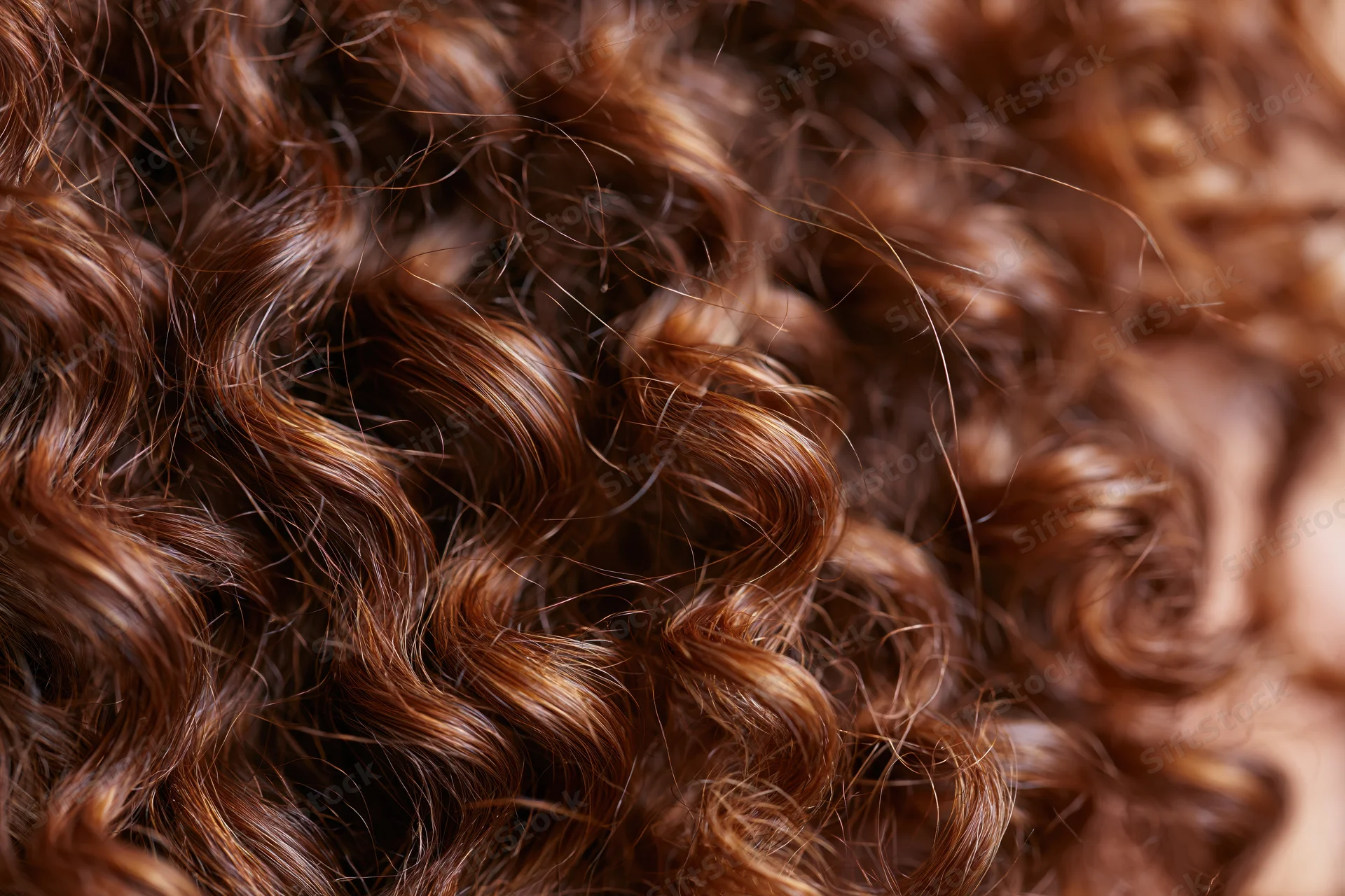 Close-up of dense curly brown hair with natural shine and texture