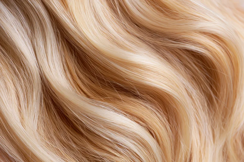 Close-up of flowing blonde hair strands with wavy texture and natural highlights