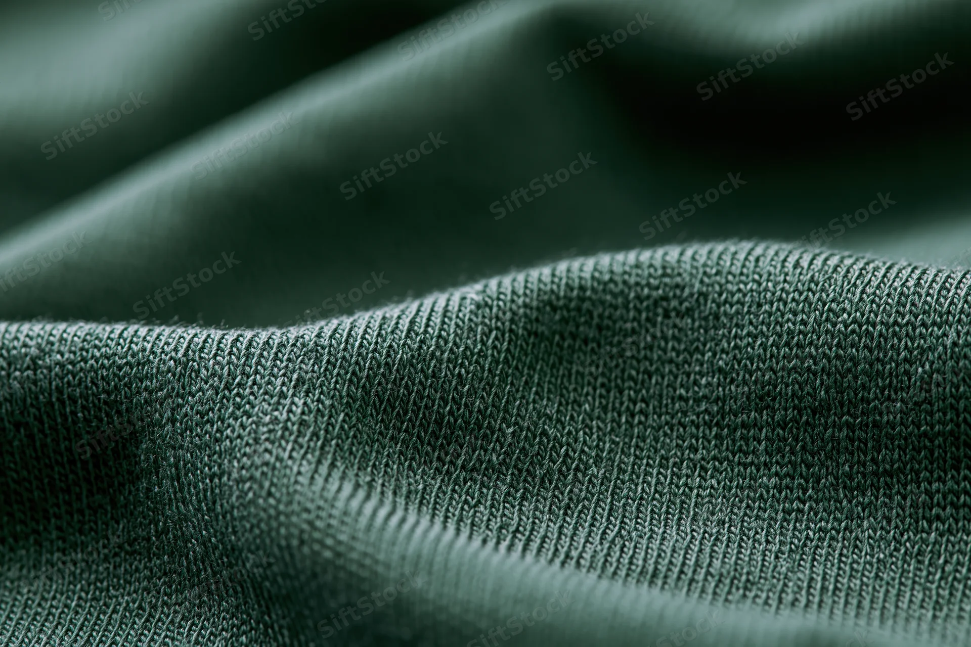 Close-up of forest green cotton jersey knit fabric showing detailed texture and weave