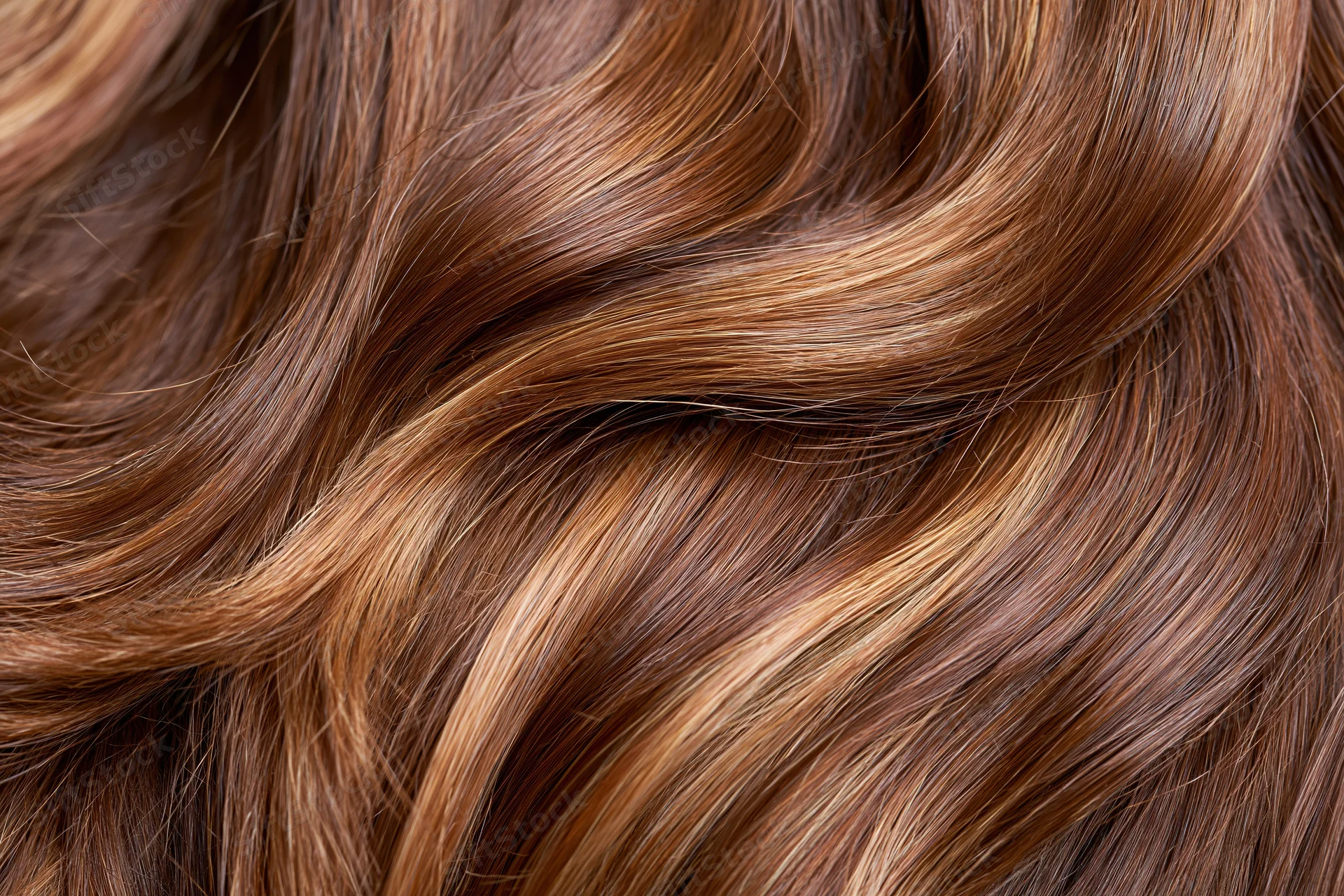Close-up of glossy brown wavy hair strands with warm highlights