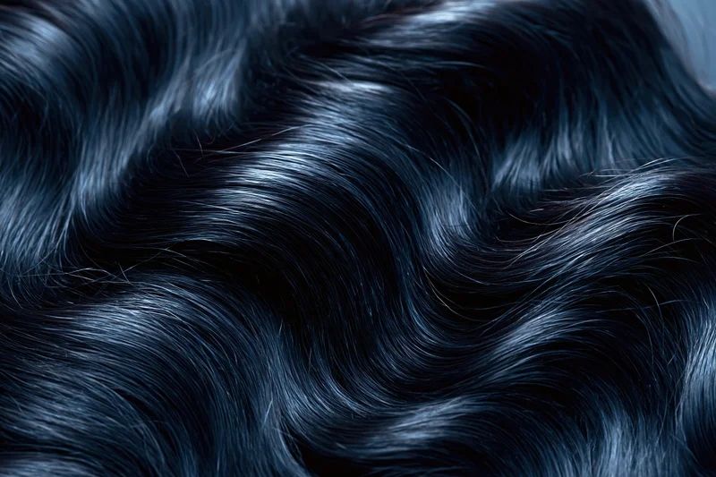 Close-up of glossy dark black wavy hair strands showing natural texture and shine
