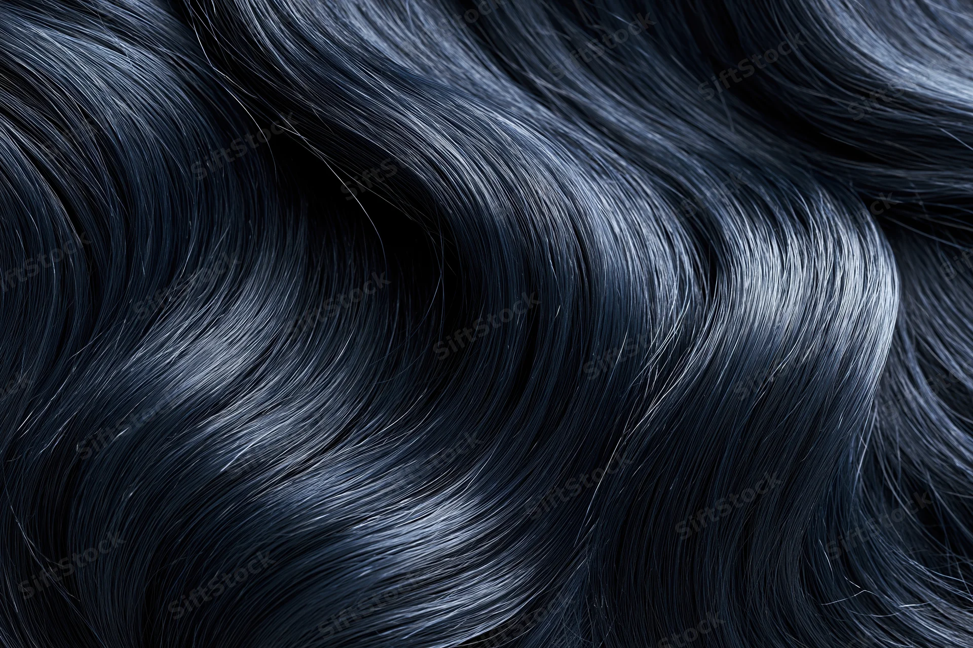 Close-up of glossy dark black wavy hair strands in soft light