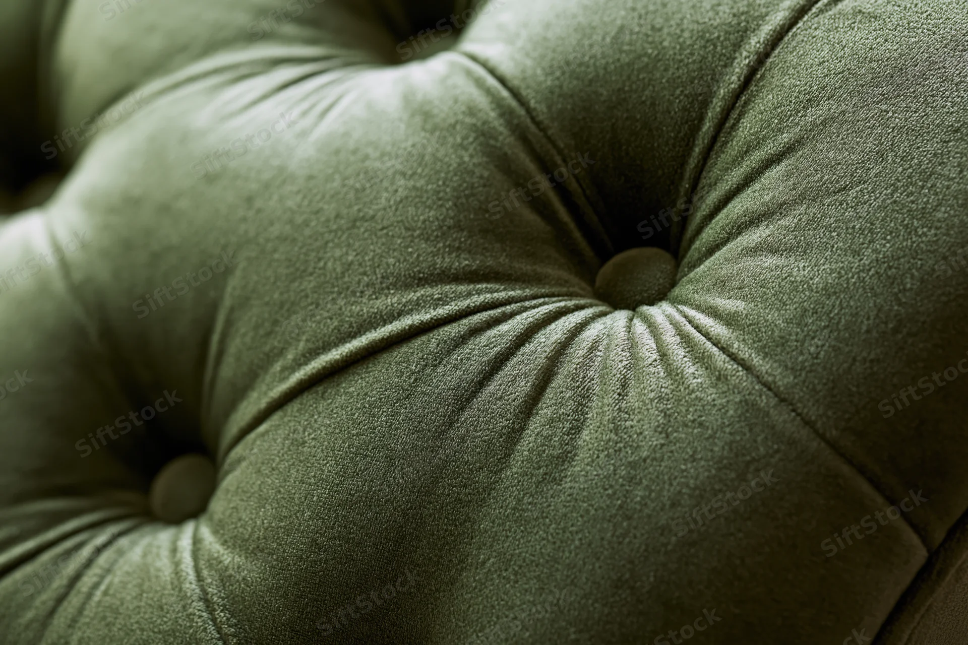 Close-up of tufted olive green velvet chesterfield sofa upholstery