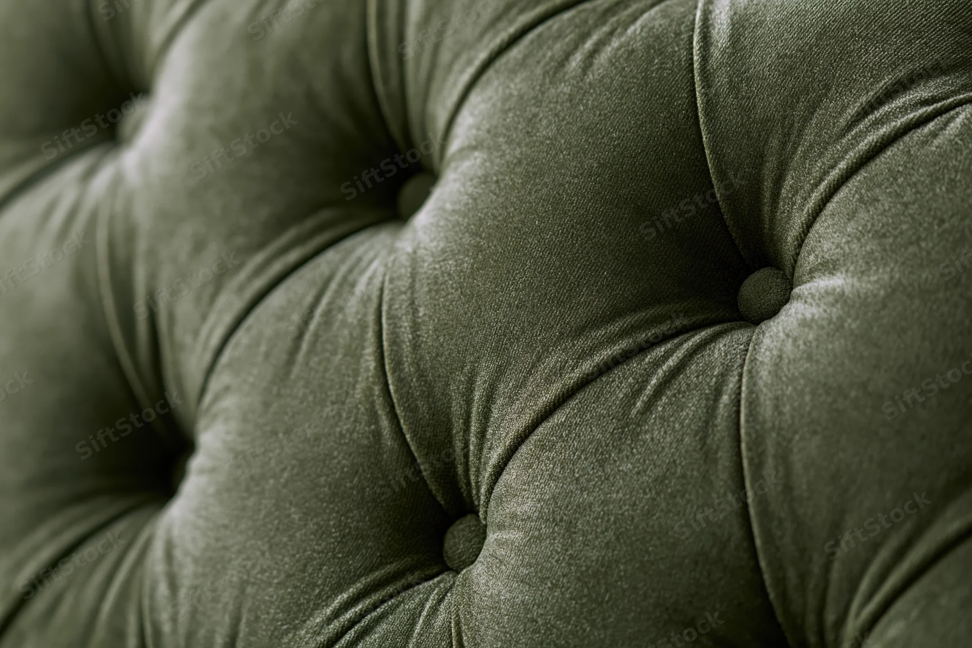 Close-up of olive green velvet tufted chesterfield sofa upholstery