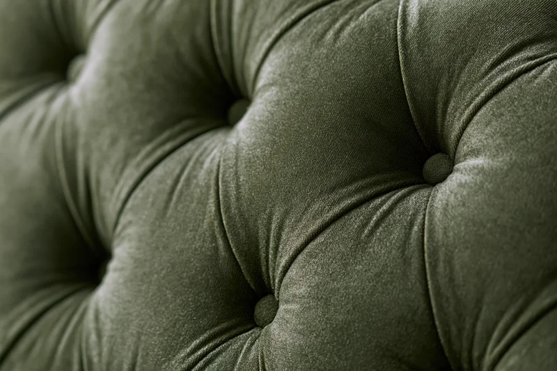 Close-up of olive green velvet tufted chesterfield sofa upholstery