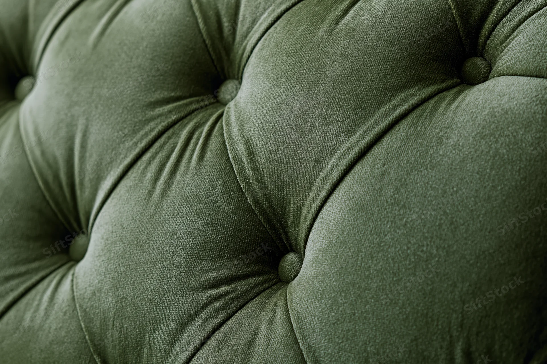 Close-up of olive green velvet tufted chesterfield sofa upholstery