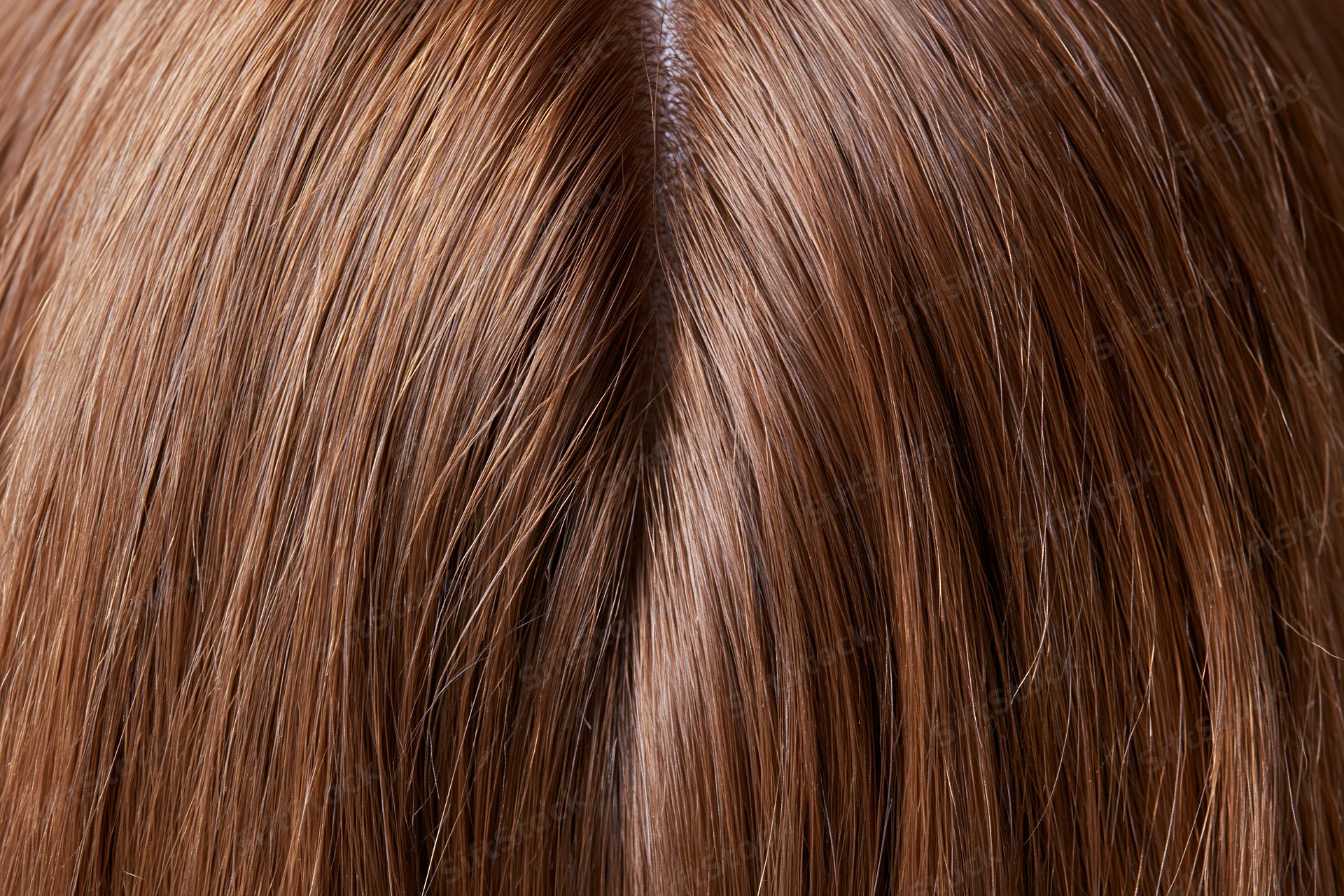 Close-up of straight brown human hair with visible parting and scalp texture