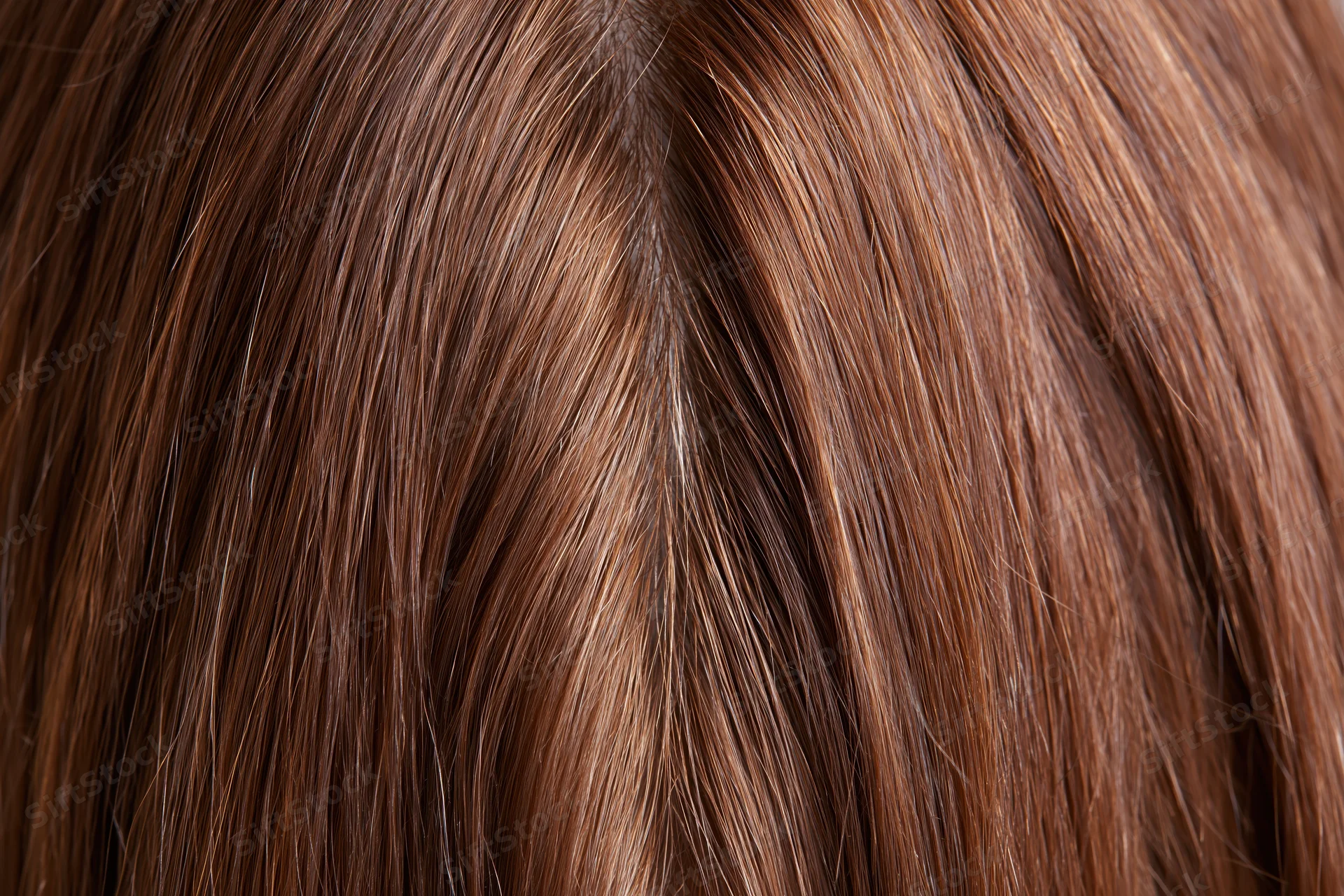 Close-up of straight brown human hair with visible parting and scalp texture
