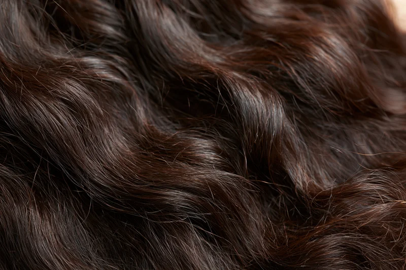 Close-up of thick dark brown wavy hair filling the frame