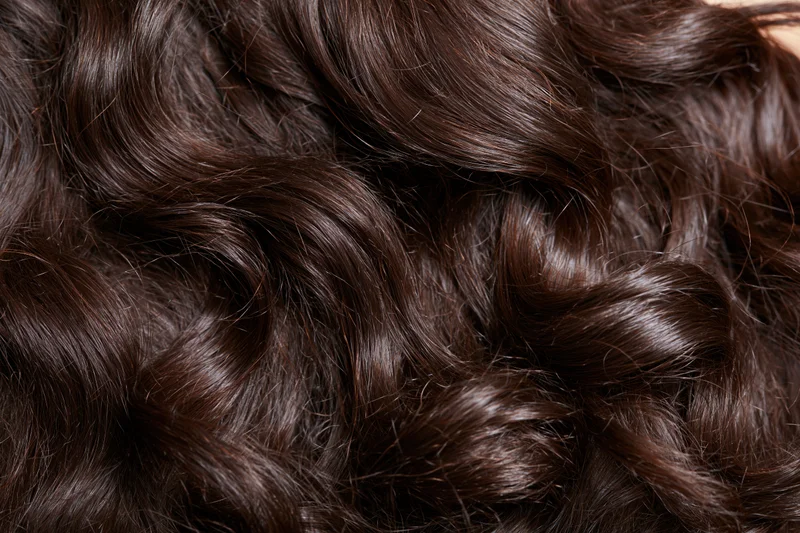Close-up of thick dark brown wavy hair filling the frame