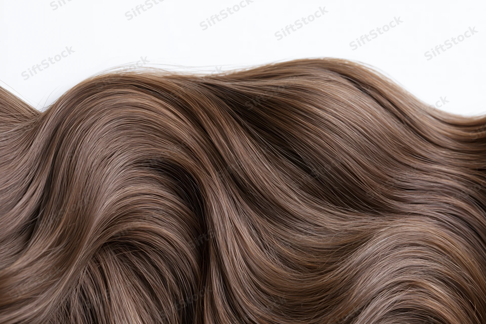 Close-up of thick wavy brown hair strands arranged in flowing waves against white background
