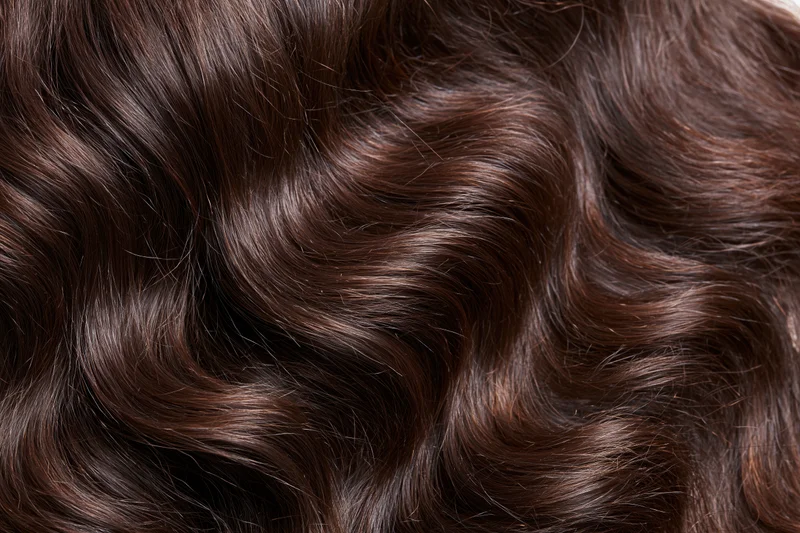 Close-up of thick wavy dark brown hair filling the frame