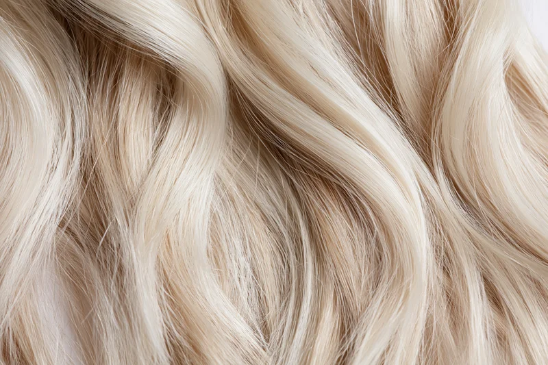 Close-up of wavy blonde hair strands with natural texture and shine