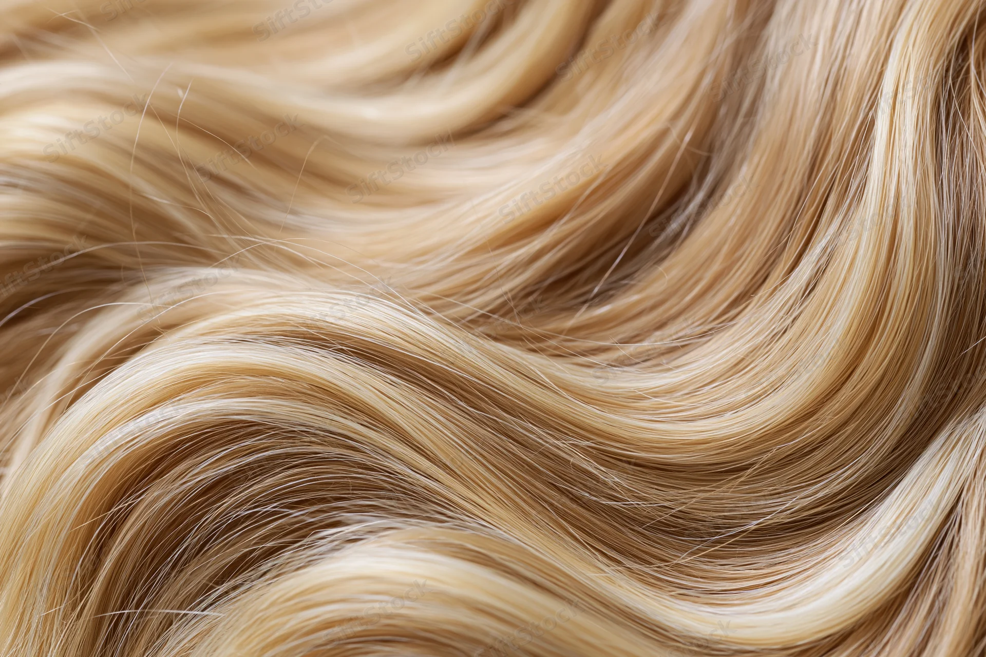 Close-up of wavy blonde human hair filling the frame with soft texture and natural shine