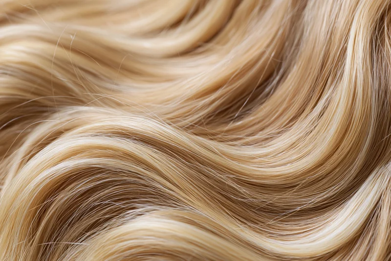 Close-up of wavy blonde human hair filling the frame with soft texture and natural shine