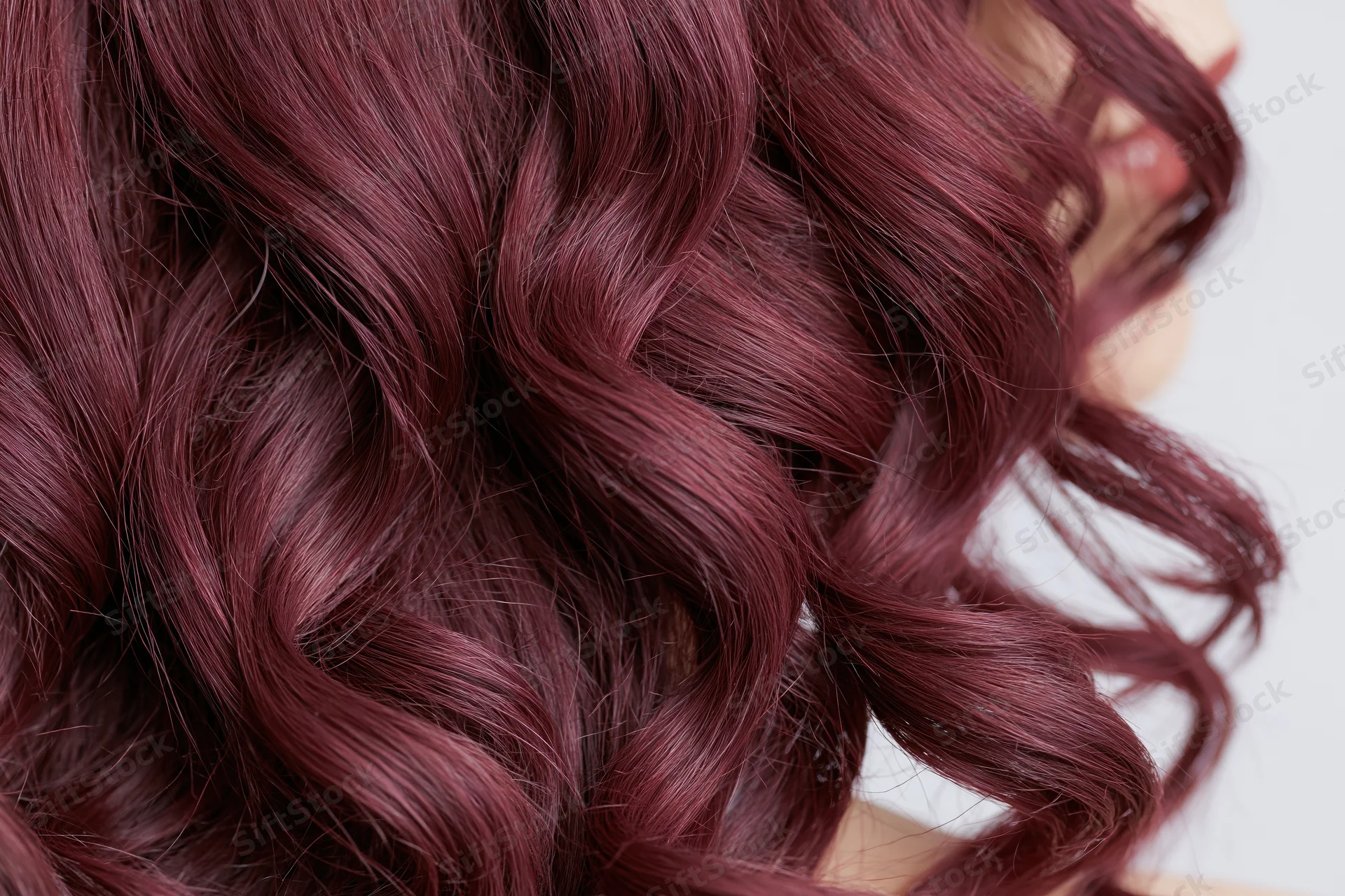 Close-up of wavy burgundy-red hair with glossy texture filling the frame