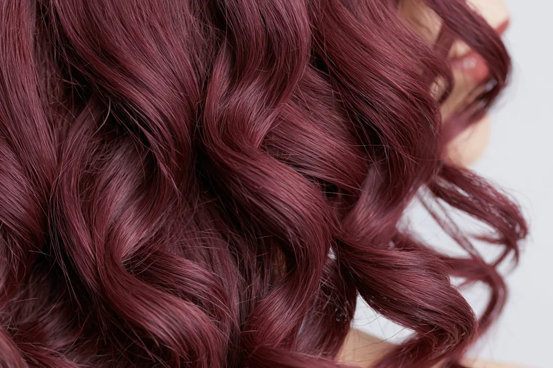 Close-up of wavy burgundy-red hair with glossy texture filling the frame