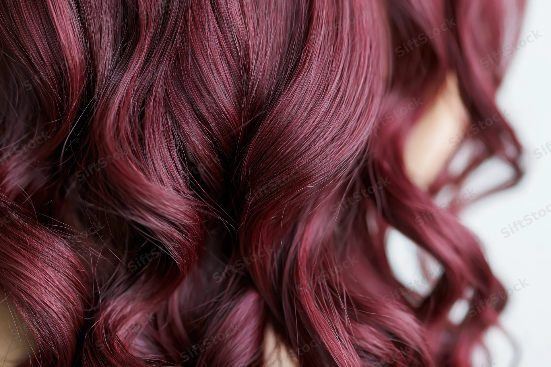 Close-up of wavy burgundy-red hair with glossy texture filling the frame