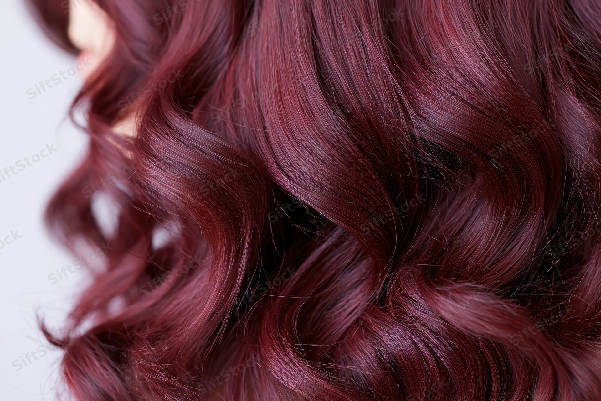 Close-up of wavy burgundy-red hair on a woman's head