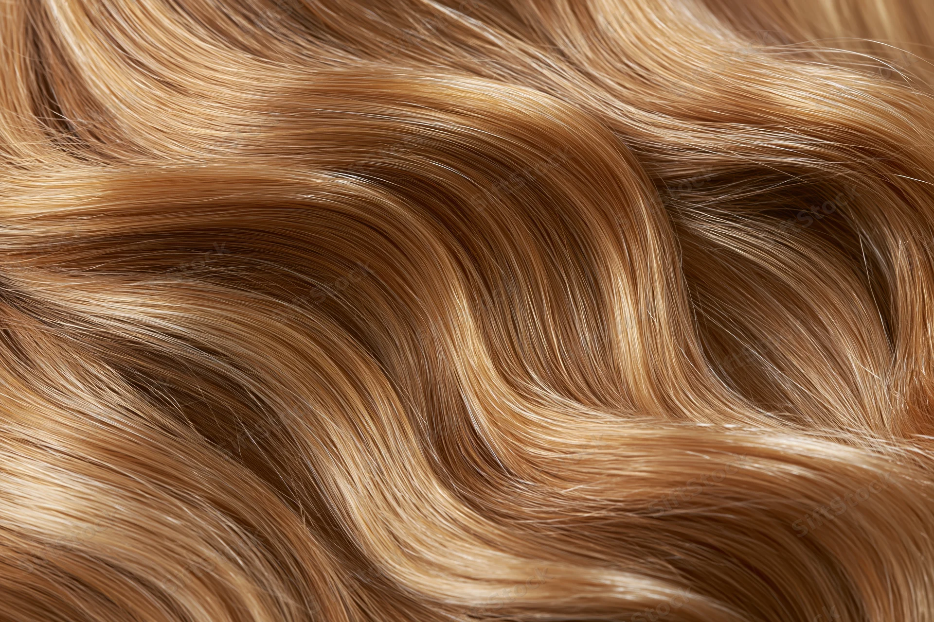 Close-up of wavy blonde and brown human hair with glossy texture filling the frame