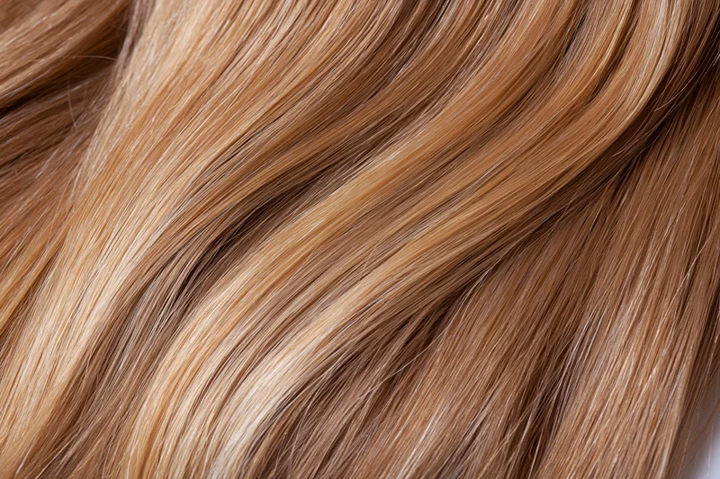 Close-up of straight honey-blonde human hair showing smooth texture and natural shine