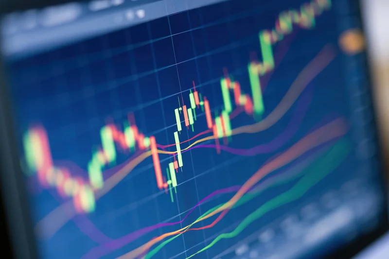 Close-up of a trading monitor screen displaying candlestick chart with moving averages and financial indicators