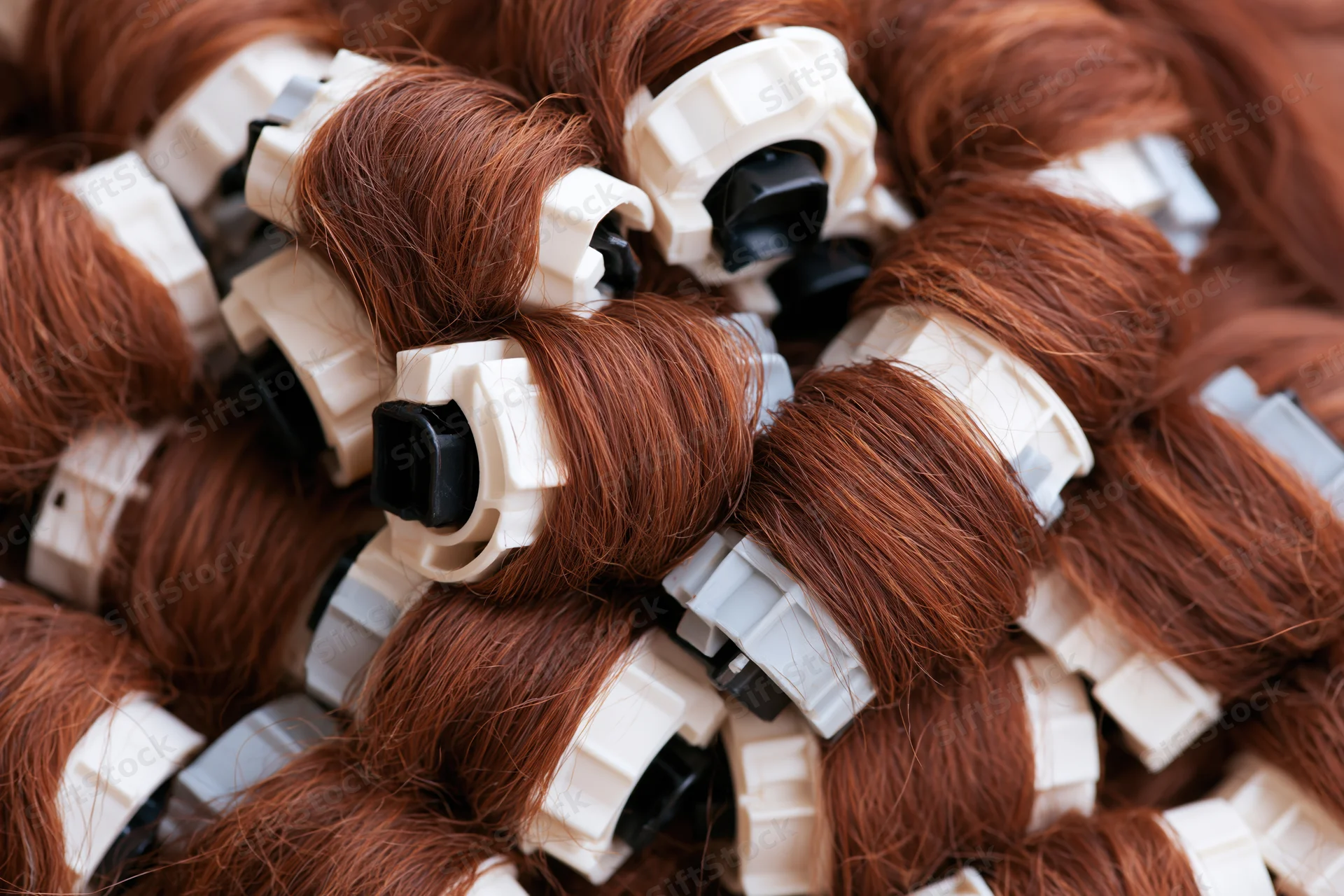 Auburn hair extensions tightly wound on white plastic clips in a pile