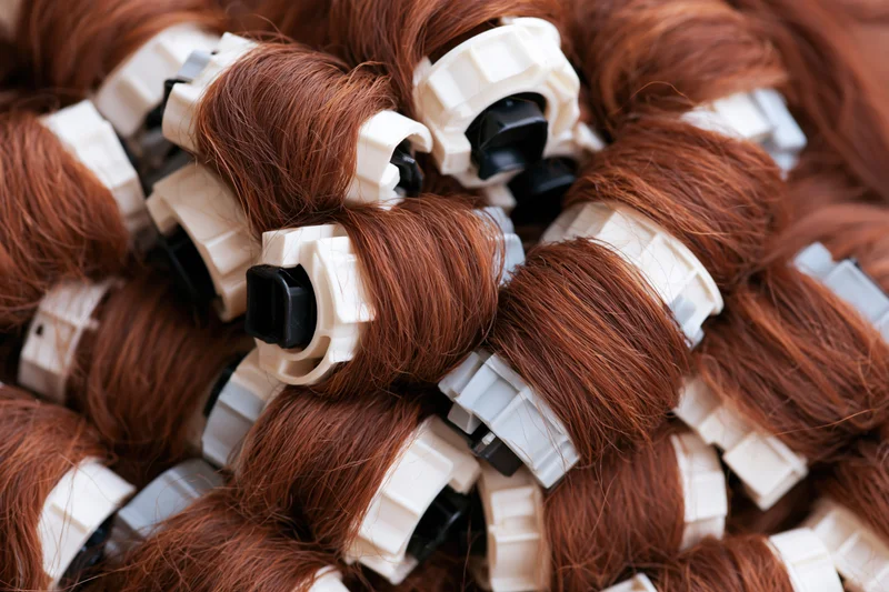Auburn hair extensions tightly wound on white plastic clips in a pile