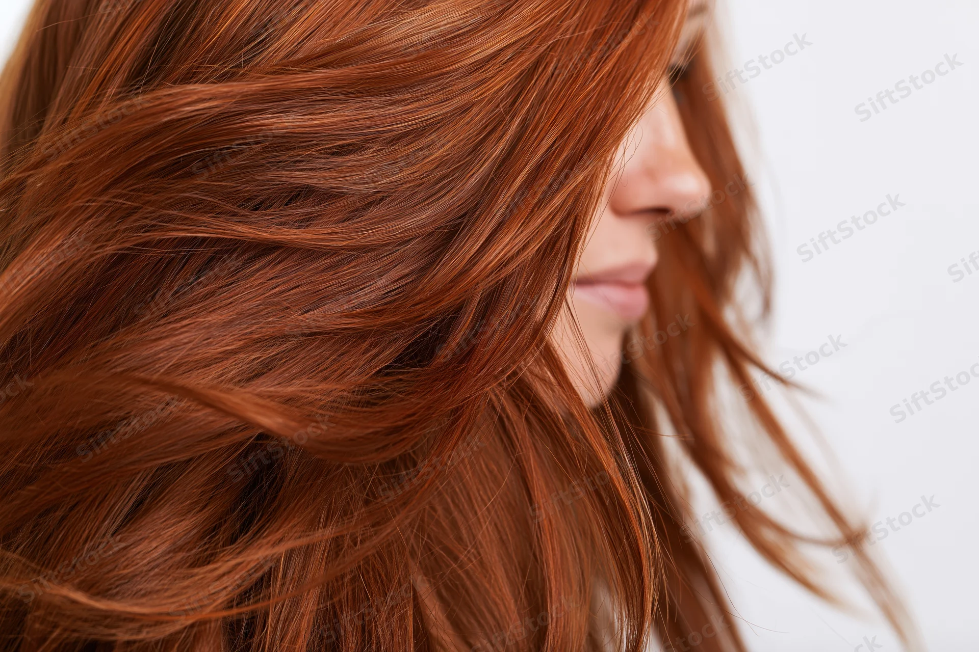 Close-up of flowing auburn red hair mid-motion on a woman in side profile