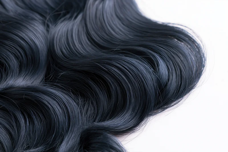Close-up of long glossy black wavy hair spread across a clean white surface