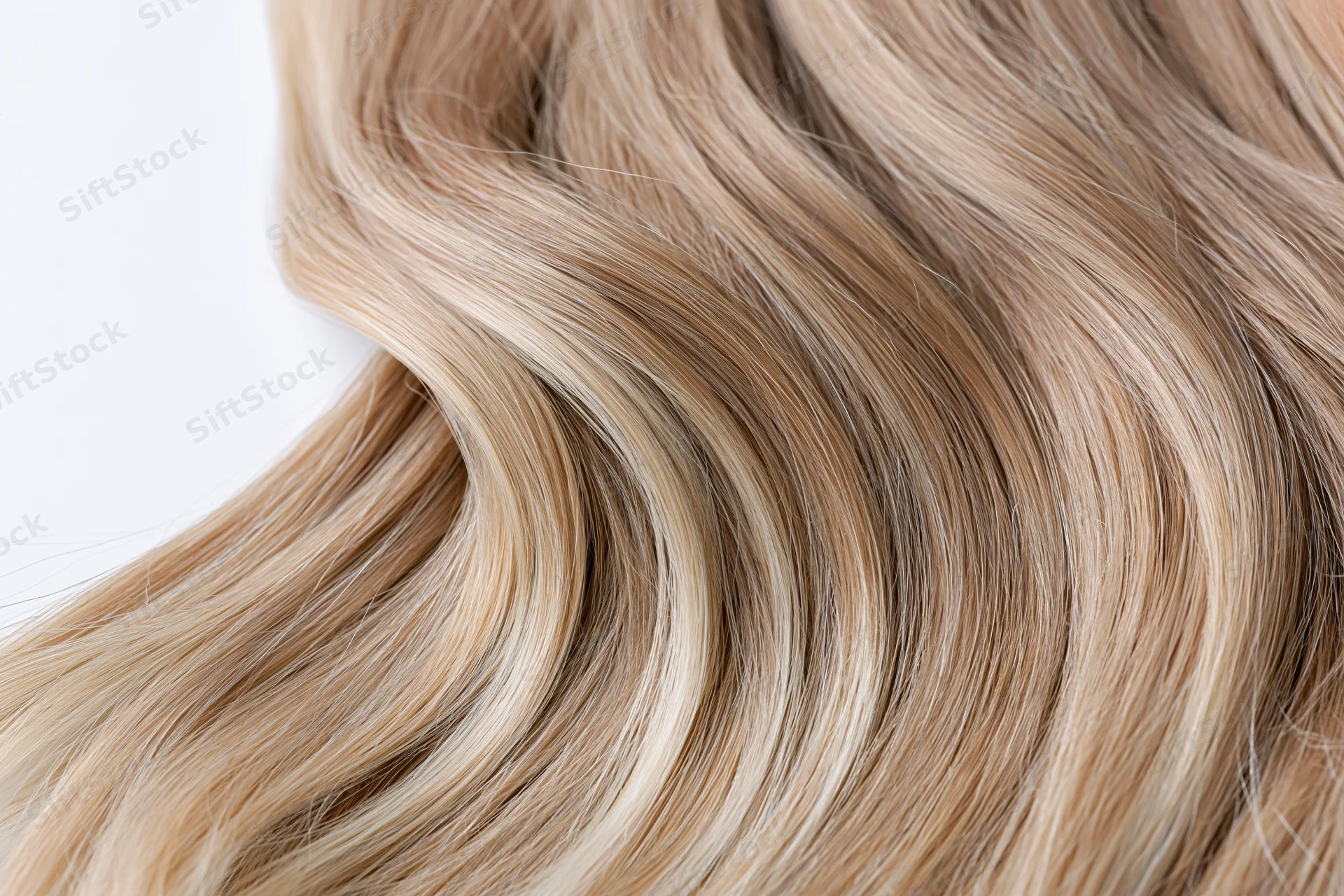 Close-up of loose wavy blonde hair strands arranged in soft flowing texture on white background