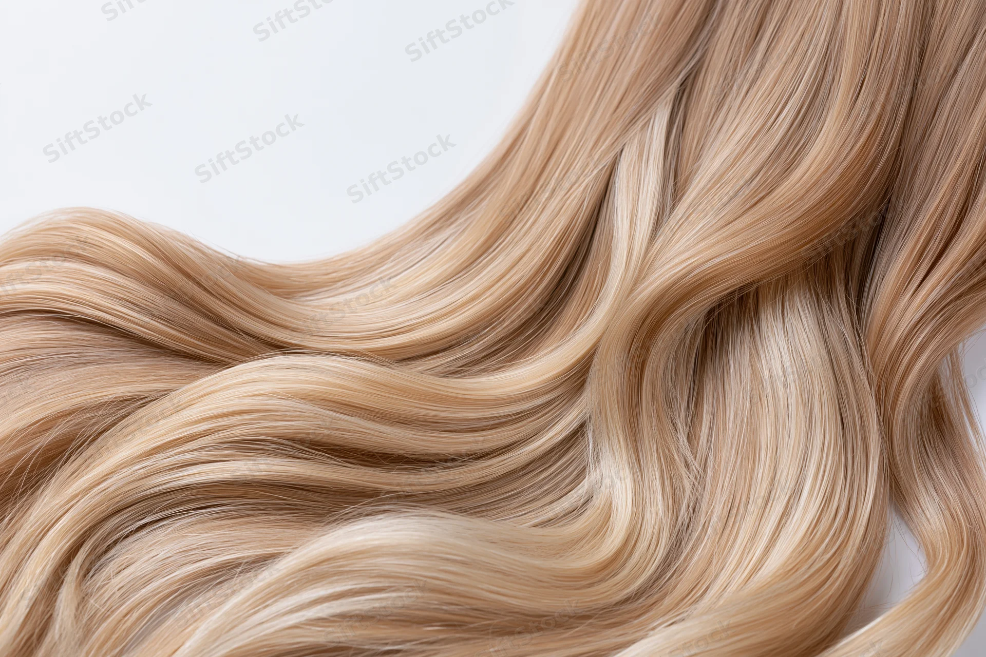 Close-up of loose wavy blonde hair strands arranged in soft flowing waves against white background