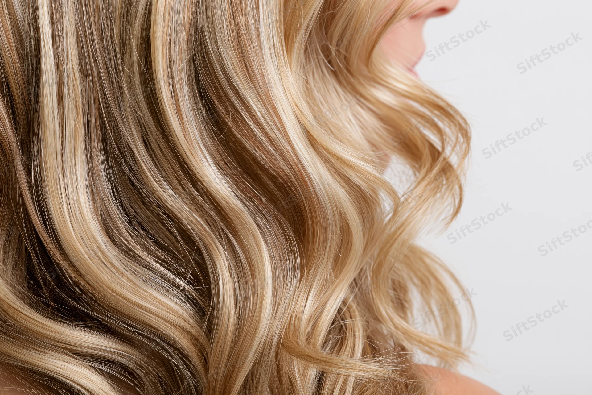 Close-up of thick wavy blonde hair with natural highlights on a woman's head
