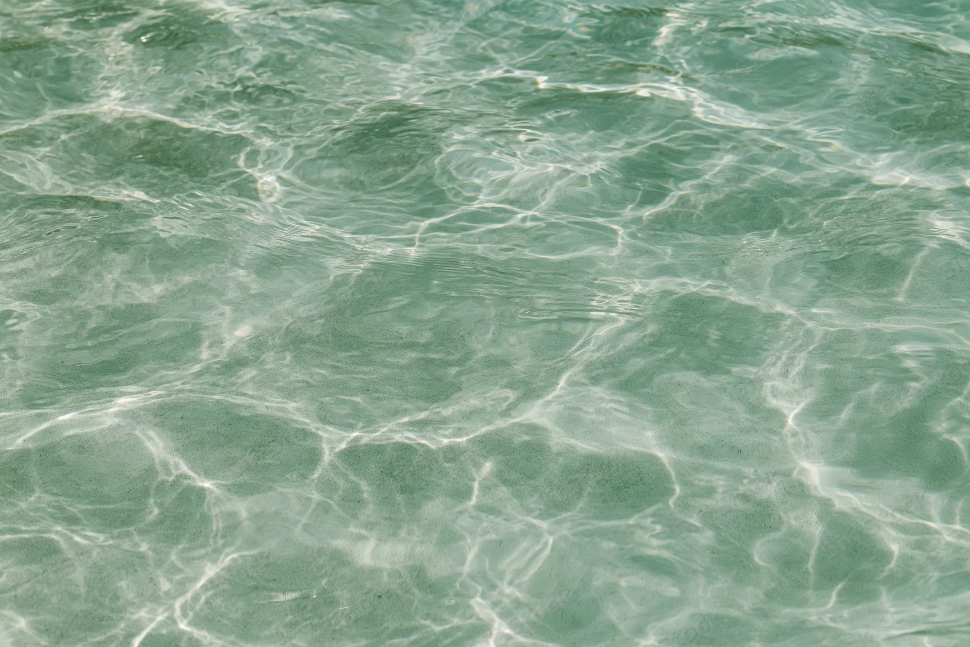 Close-up of rippling shallow pool water surface with light reflections and caustic patterns