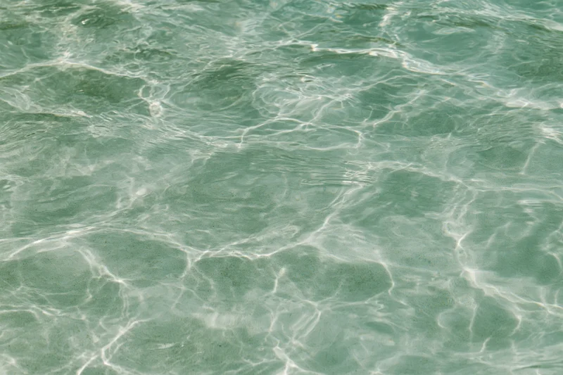 Close-up of rippling shallow pool water surface with light reflections and caustic patterns