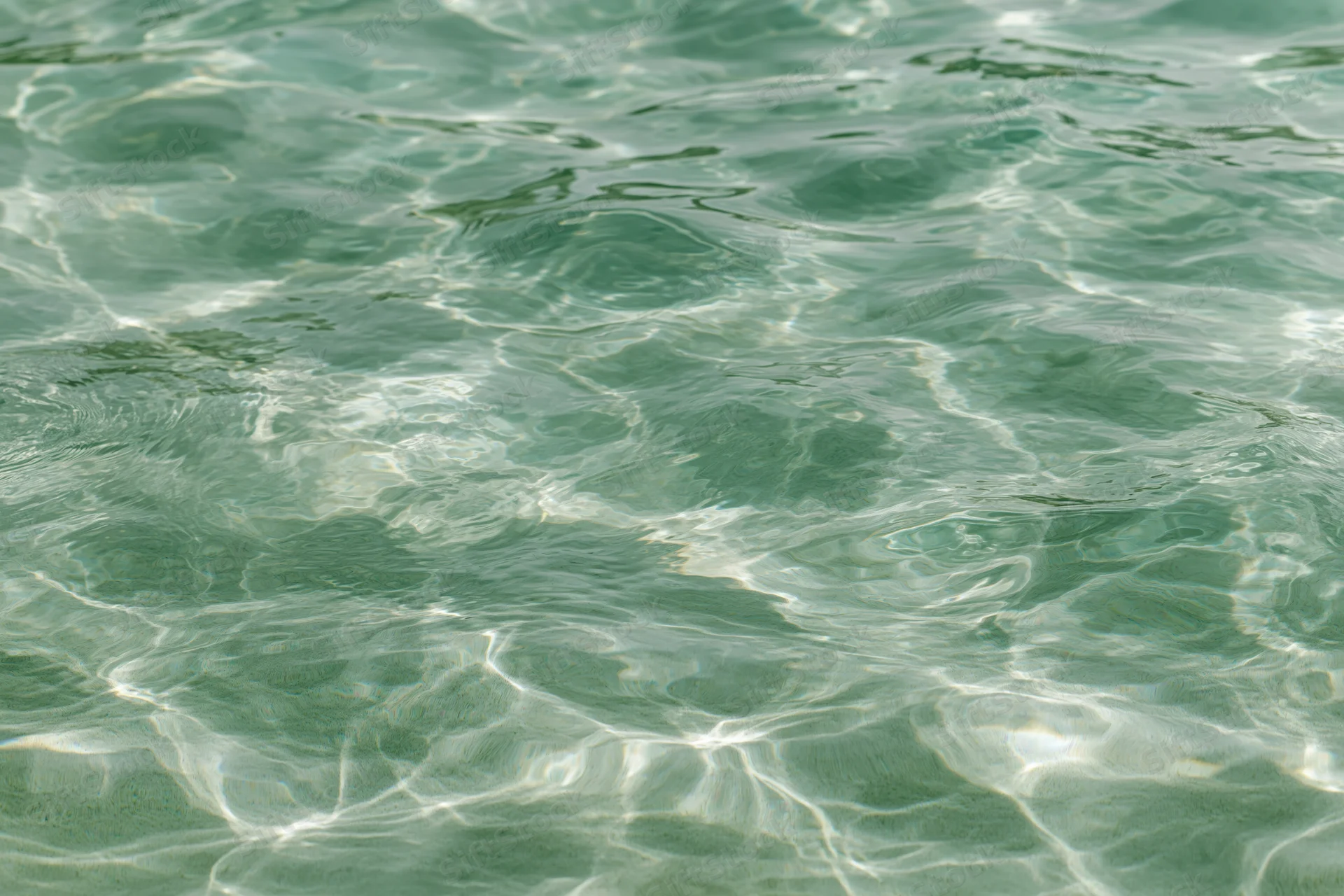 Overhead closeup of rippling shallow pool water surface with light reflections