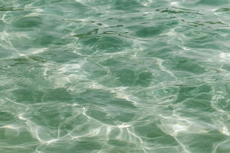 Overhead closeup of rippling shallow pool water surface with light reflections