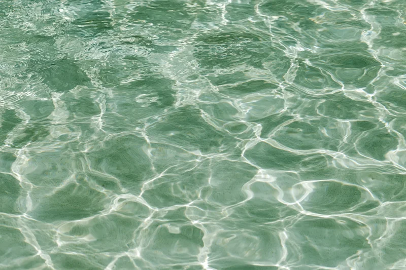 Overhead view of shallow pool water surface with ripples and light reflections