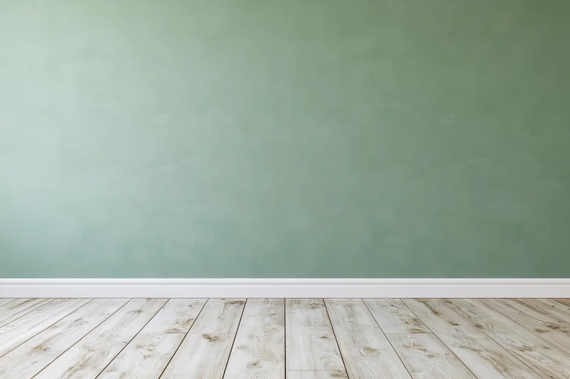 Empty room with sage green painted wall and light wooden floor