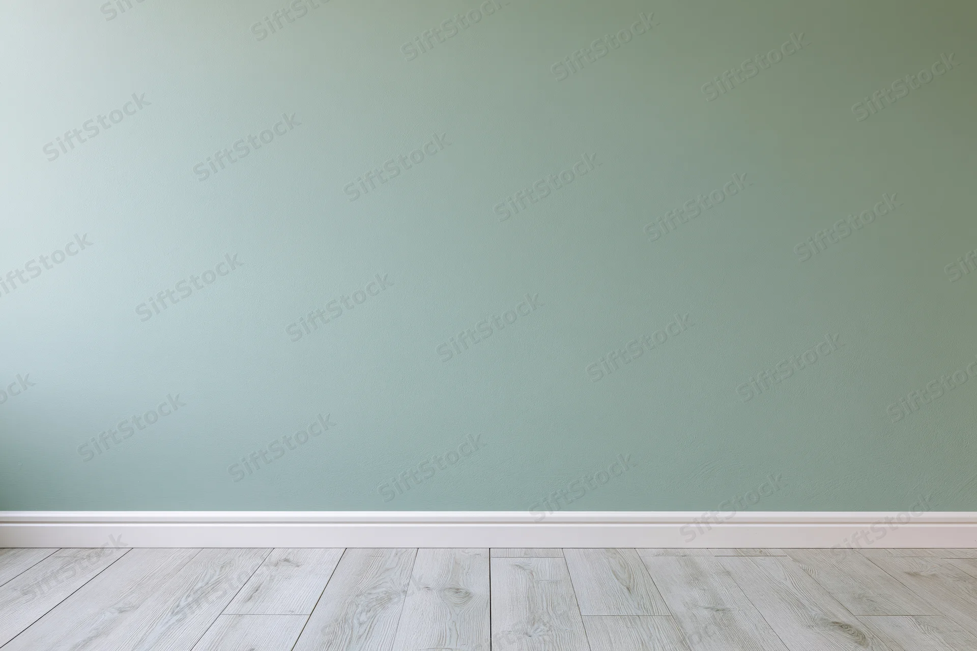 Empty interior room with sage green painted wall and light wood flooring
