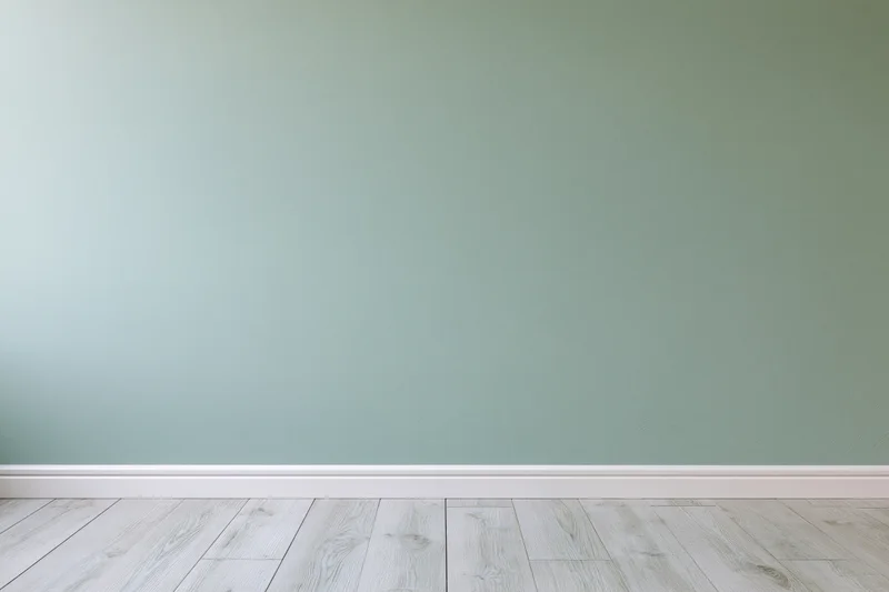 Empty interior room with sage green painted wall and light wood flooring