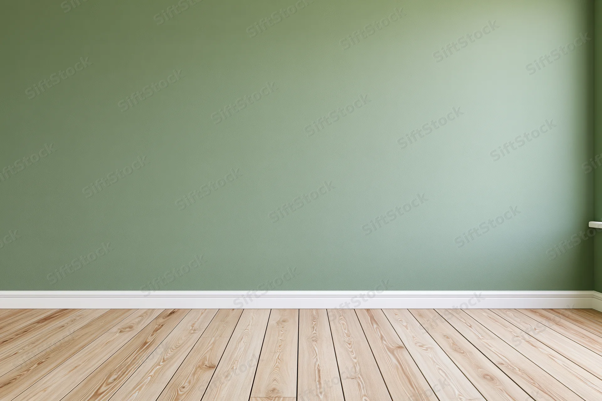 Empty room with sage green painted wall and wooden floor, featuring white baseboard and corner view