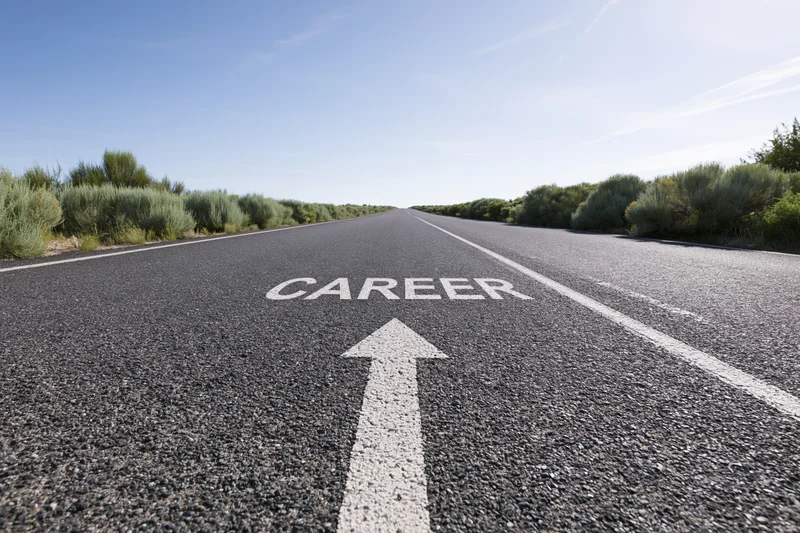 Straight asphalt road with white arrow and career text pointing forward under clear blue sky