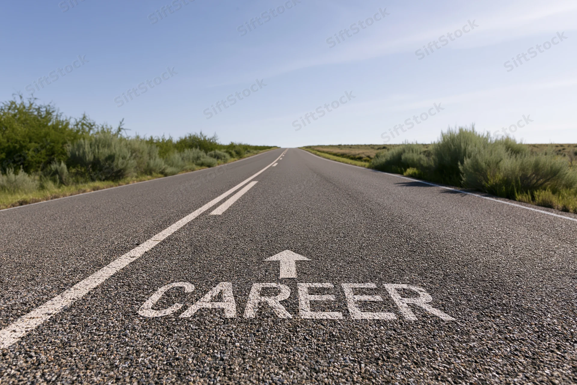 Asphalt road stretching straight ahead with career written on surface and arrow pointing forward