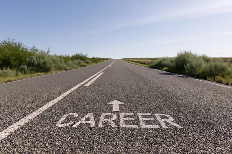 Asphalt road stretching straight ahead with career written on surface and arrow pointing forward